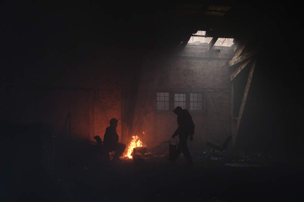 Migrants warm themselves around a fire&amp;nbsp;in the abandoned warehouse where Ali lives.&amp;nbsp;