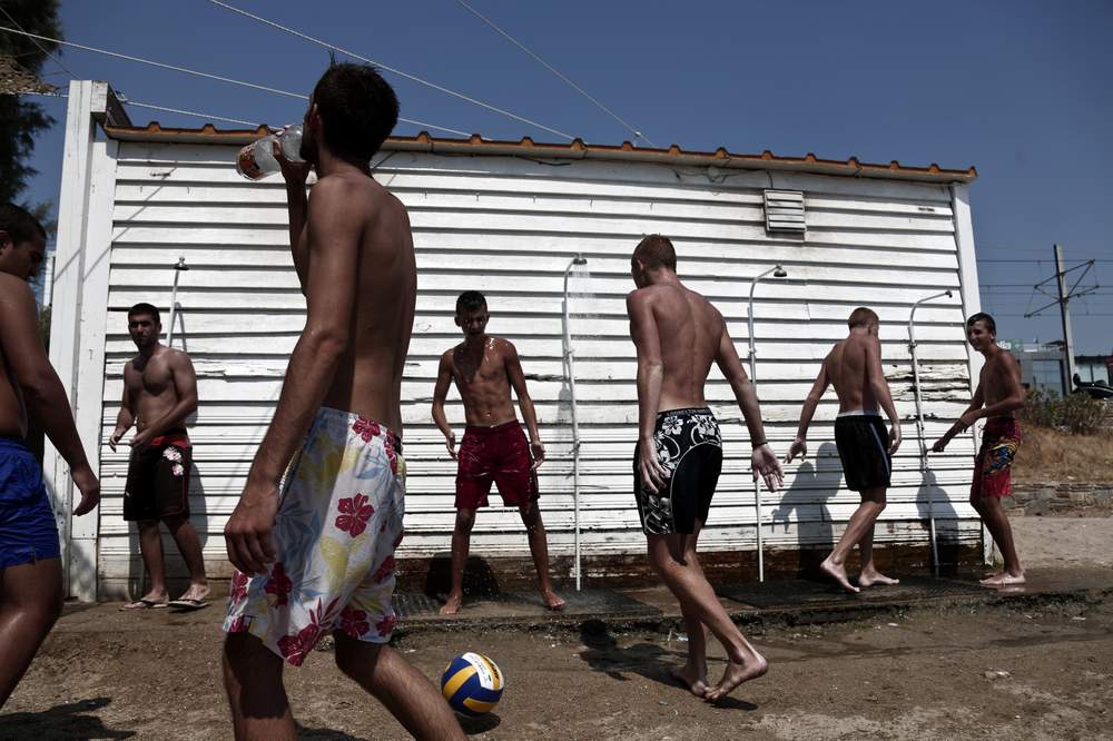 Youths shower as others play at a beach a few miles southwest of Athens, July 30, 2013. REUTERS\/Yorgos Karahalis