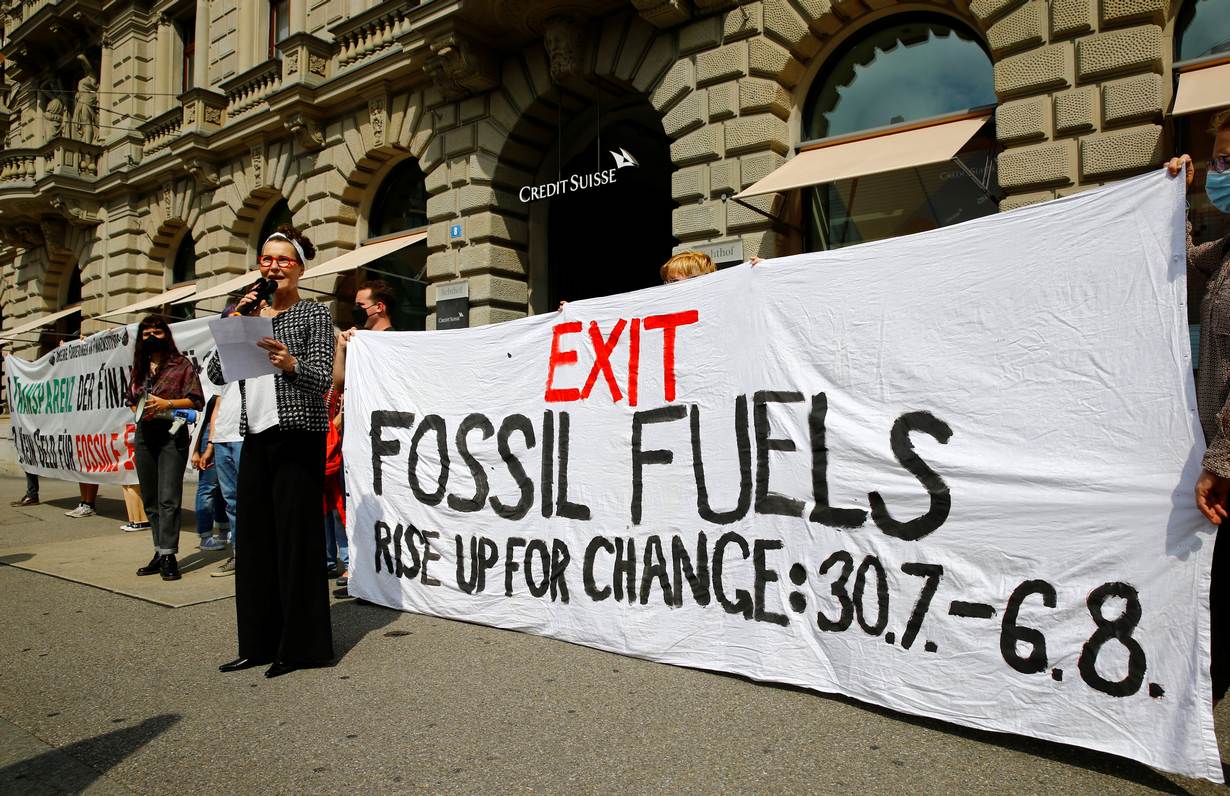A woman, introduced as a representative of the Swiss bank Credit Suisse, speaks as climate activists of the 'Rise up for Change' coalition display a banner to protest in front of the bank's headquarters in Zurich, Switzerland, July 26, 2021. REUTERS/Arnd WIegmann