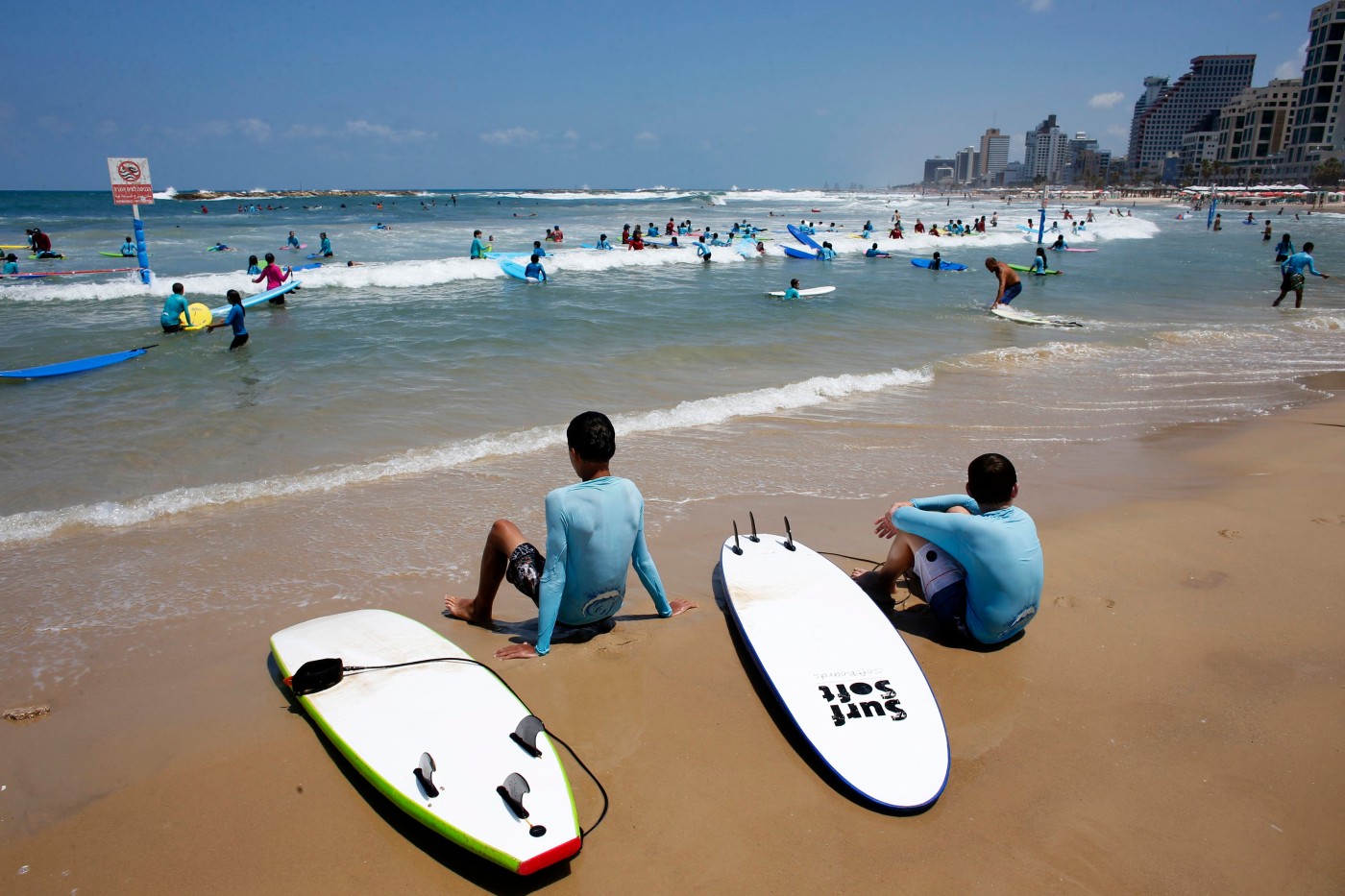 Israeli children sit on the shore during a surfing lesson at the beach