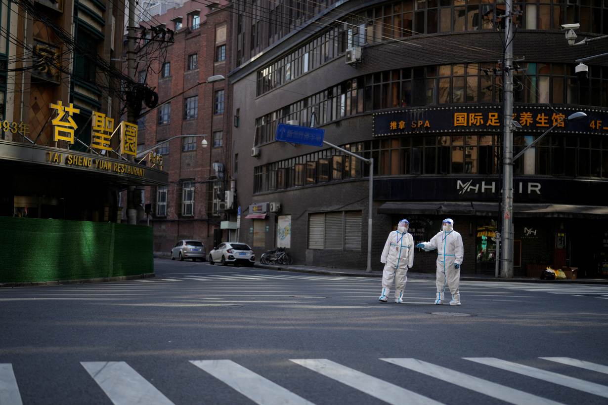 Workers in protective suits keep watch on a street during a lockdown, amid the coronavirus disease (COVID-19) pandemic, in Shanghai, China, April 16, 2022. REUTERS/Aly Song