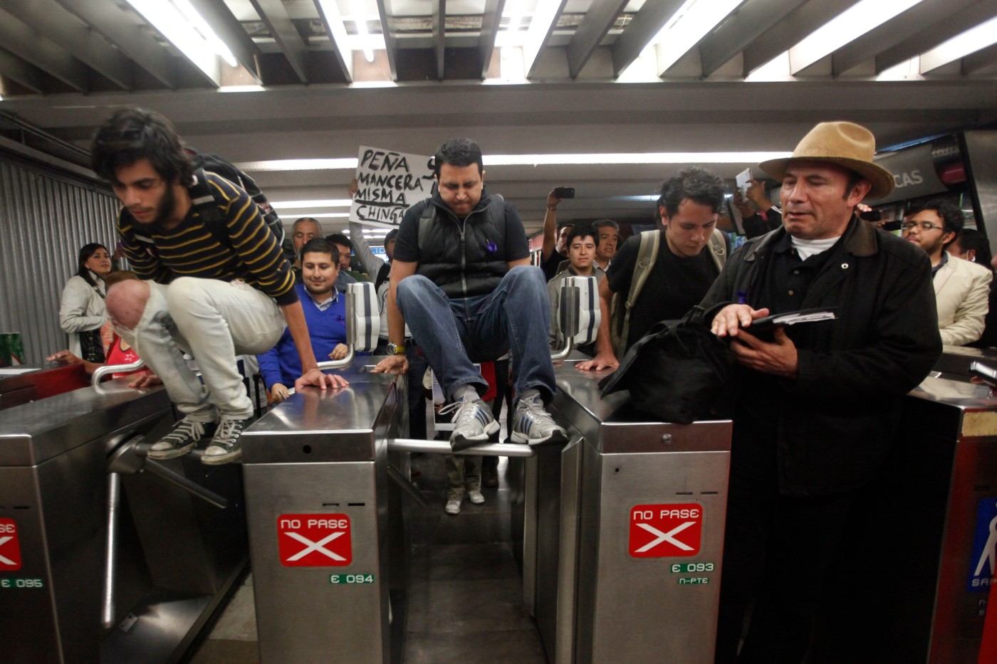 People jump over the turnstiles at the subway without paying to protest against a fare hike, at