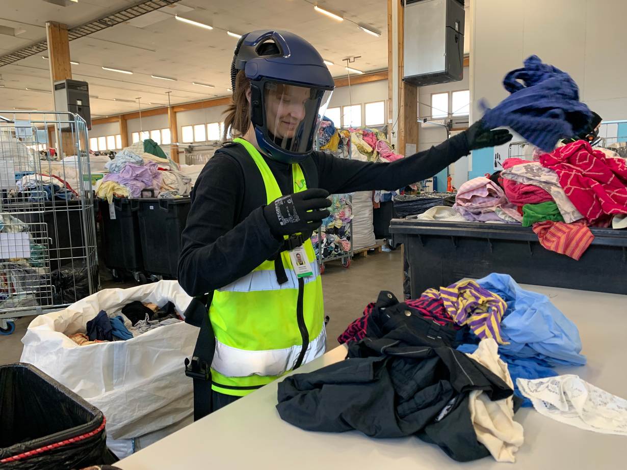 Wearing a breathing apparatus to keep out pollutants, Sallamari Salmi sorts textiles as part of a recycling campaign in Turku, Finland, on April 26, 2022. Thomson Reuters Foundation/Alister Doyle