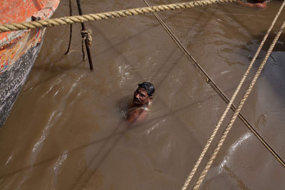A sand miner resurfaces from a dive in the Vasai Creek.