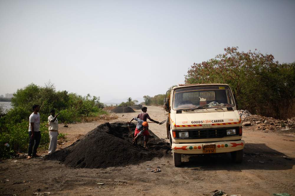 Workers load sand mined from the Vasai Creek on to a truck.