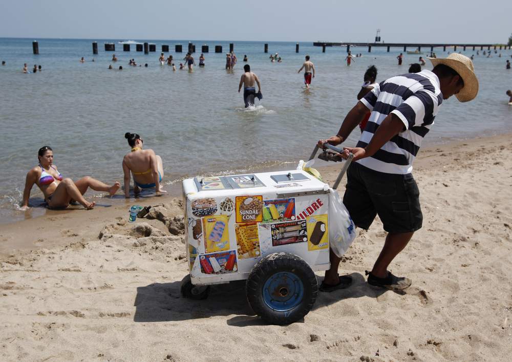 A vendor drags his ice cream cooler across North Avenue Beach in Chicago July 20, 2011, on a day when the heat index was expected to exceed 110 degrees Fahrenheit or 43 degrees Celsius.  REUTERS\/Jim Young