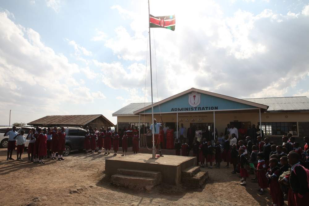 A school boy raises the Kenyan flag outside a school in Kajiado, Kenya.
