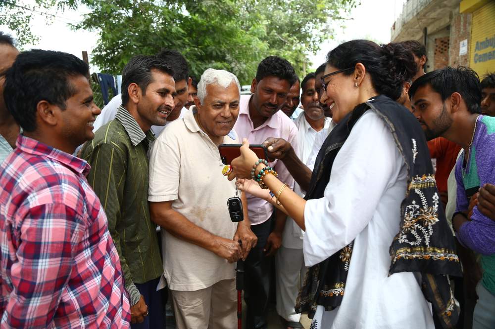 Village head Chhavi Rajawat shows her father [centre] and other villagers something on her phone.